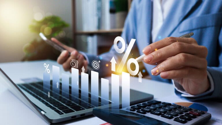 Mann sitzt vor einem Laptop und hält einen Stift in der Hand